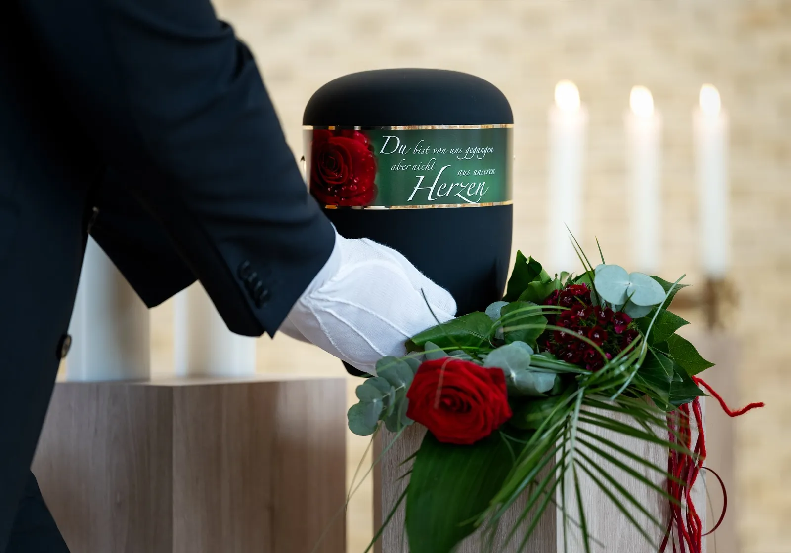 Urne mit Rosengesteck wird beigesetzt